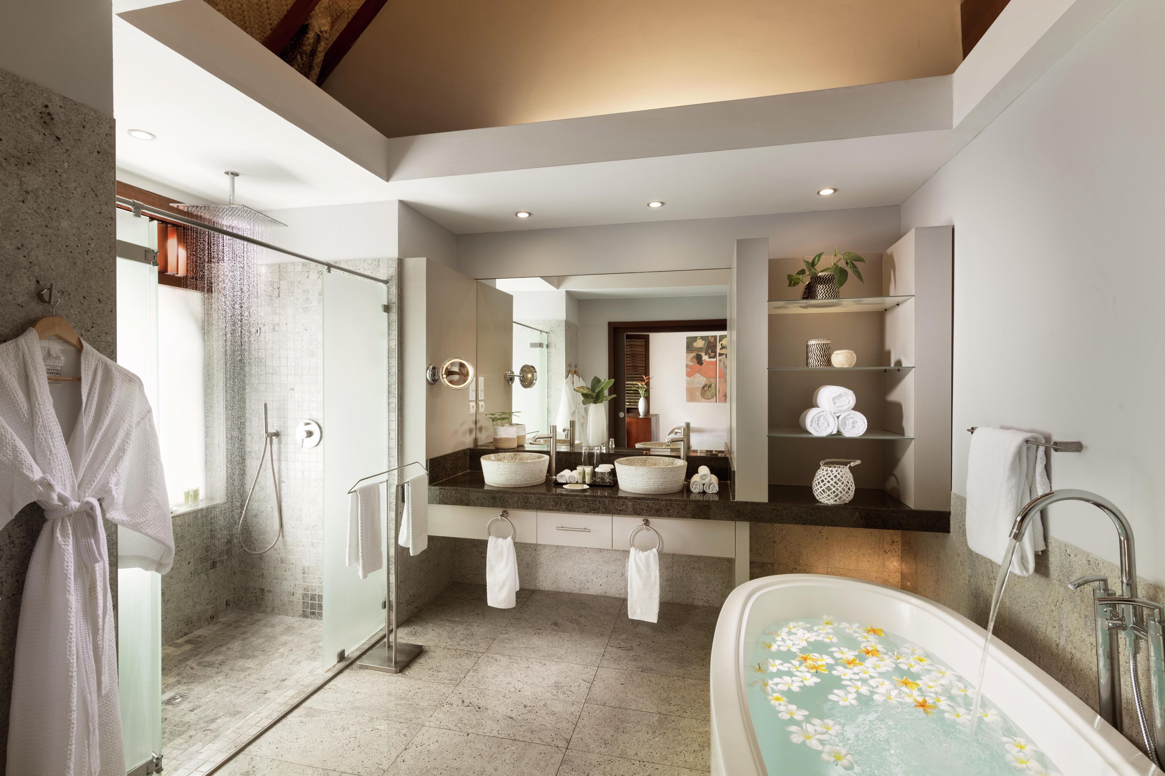 Une salle de bain moderne dotée d’une douche à parois de verre, d’une baignoire sur pieds et d’un meuble-lavabo avec deux vasques.
