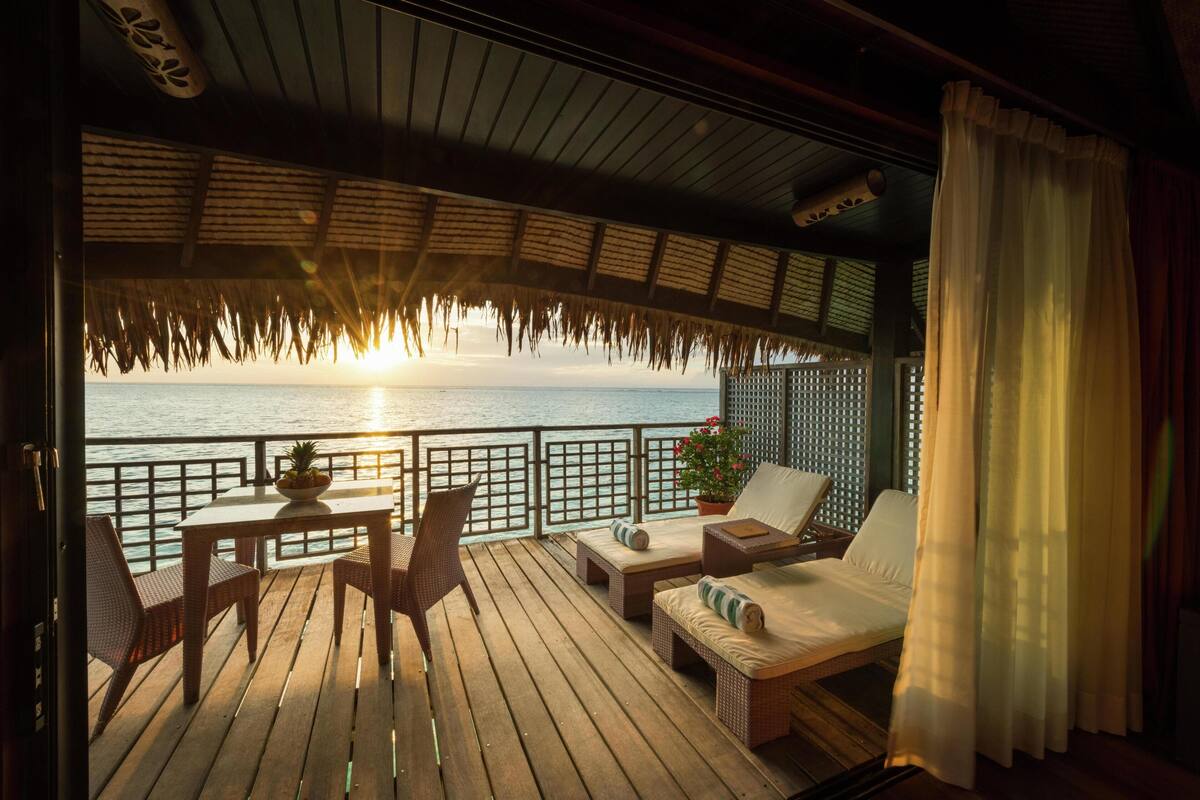 A wooden deck with a table and chairs, a sofa, and a potted plant.
