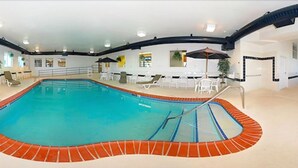 An indoor swimming pool with a tiled edge, surrounded by lounge chairs and a bar area. - Sleep Inn And Suites Danville (Danville)