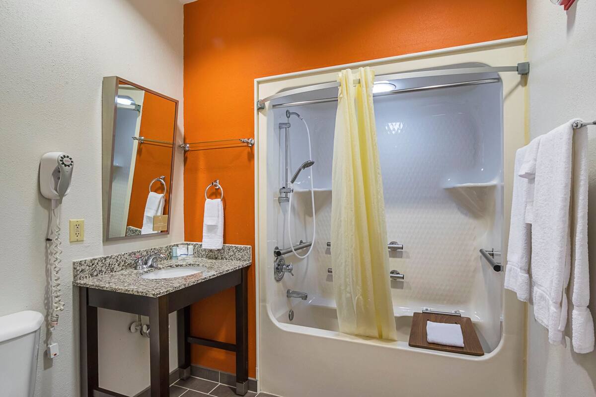 A bathroom with a sink, mirror, towel rack, and a shower with a curtain.