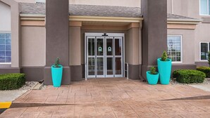 A building entrance with a revolving door, large potted plants, and a tiled walkway. - Sleep Inn And Suites Danville (Danville)