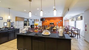 A hotel lobby with a central counter, dining area, and a clock on the wall. - Sleep Inn And Suites Danville (Danville)