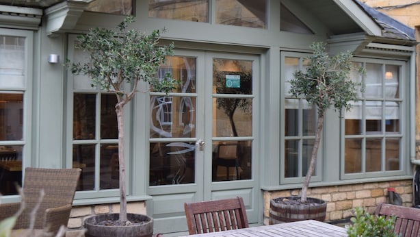 A building with large windows, a door, and potted plants. - Noel Arms Hotel (Chipping Campden)