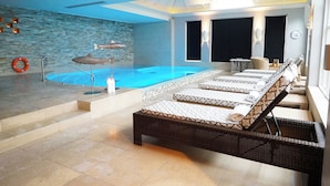 A modern indoor pool area with a lounge area, stone walls, and a ceiling with recessed lighting. - Noel Arms Hotel (Chipping Campden)