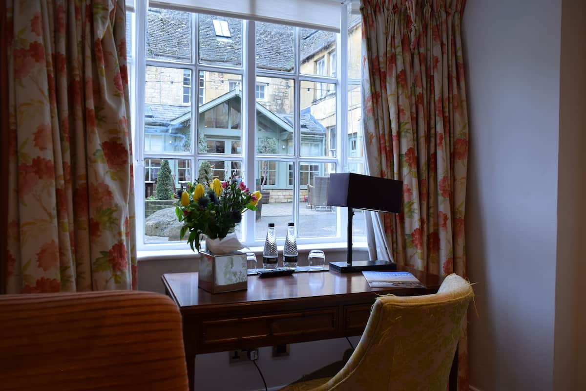 A room with a desk, chair, and a window with floral curtains.