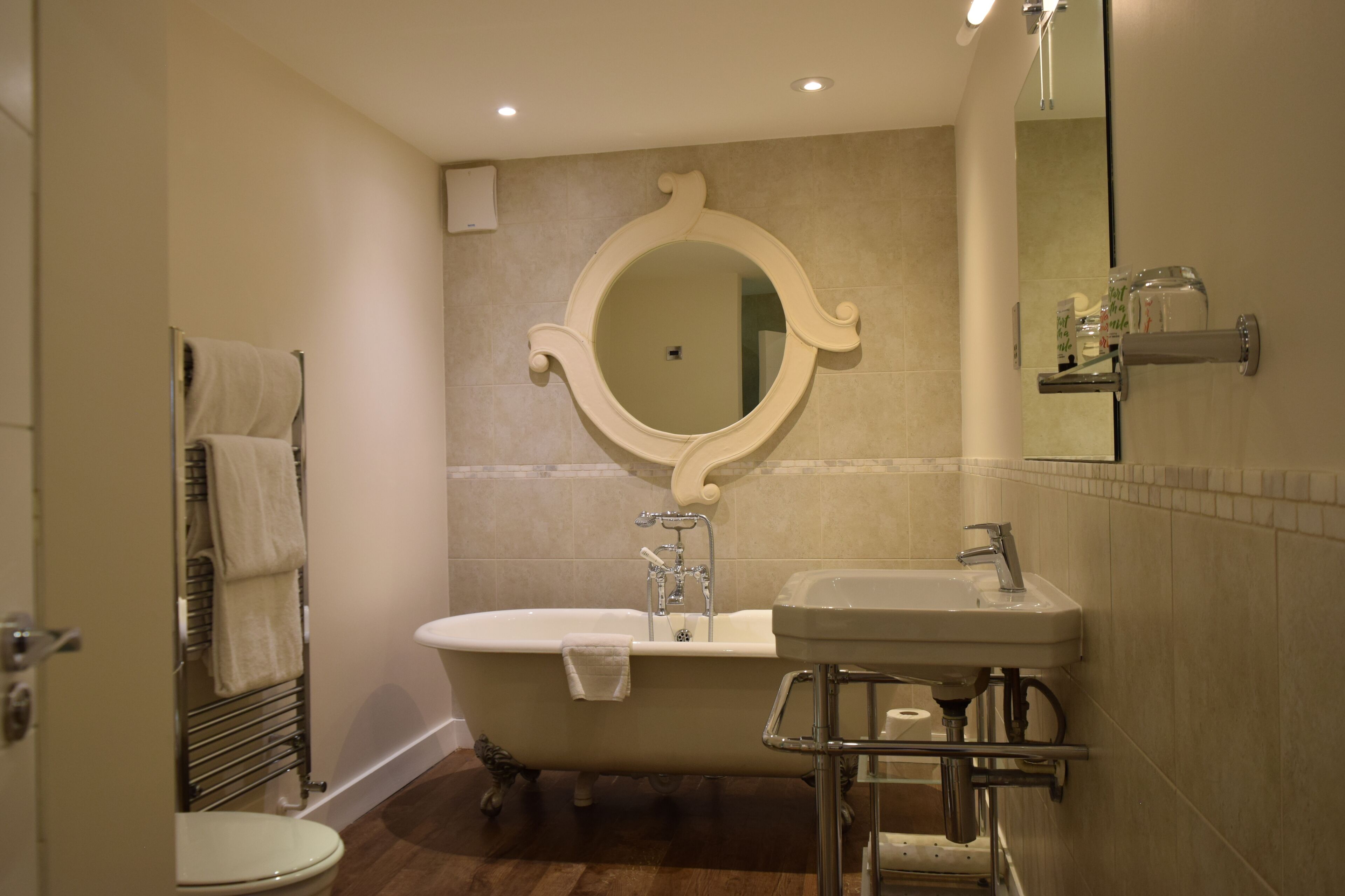 A bathroom with a bathtub, a sink, a toilet, and a mirror.