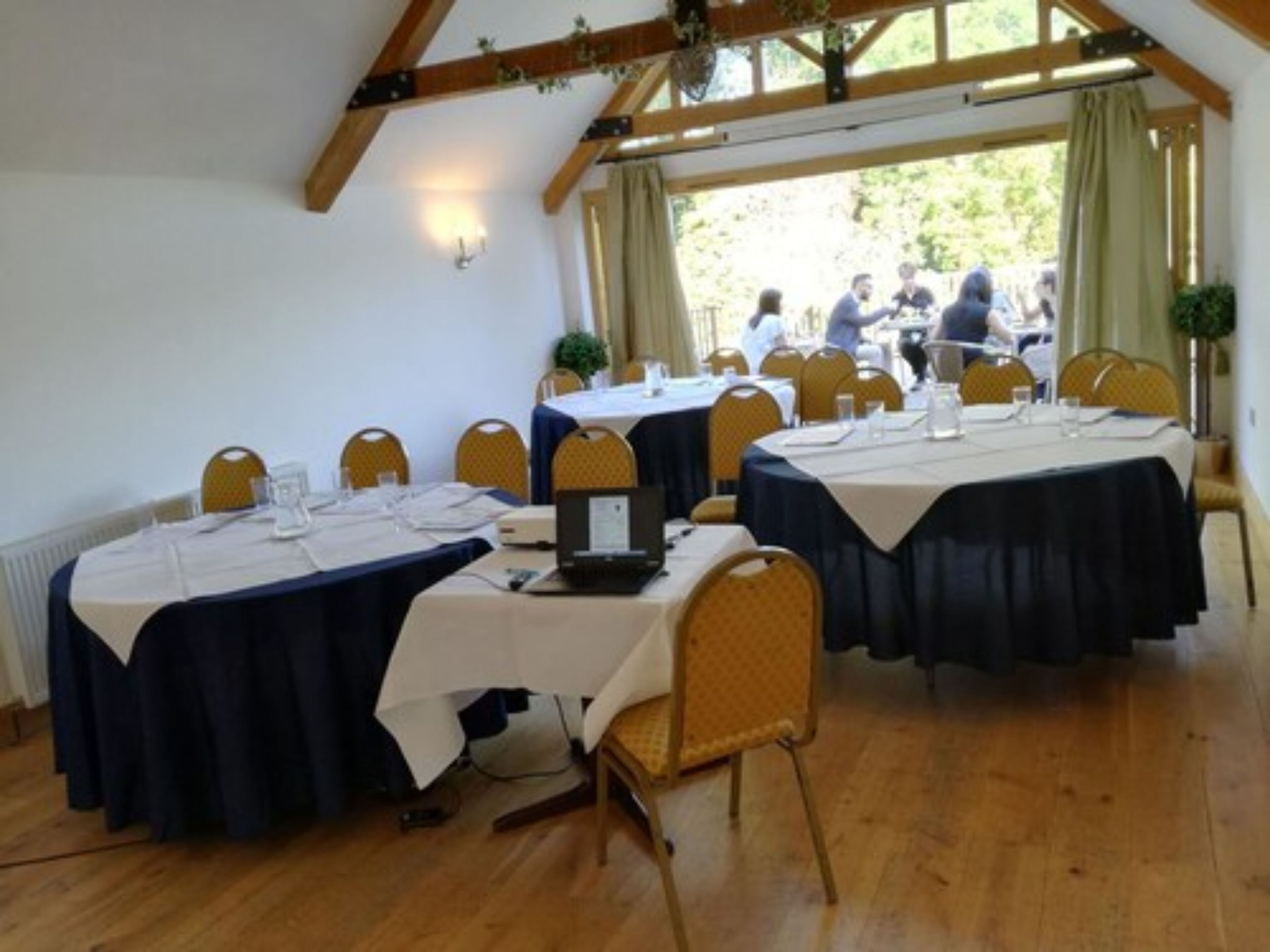 A conference room with round tables, yellow chairs, and a wooden ceiling.