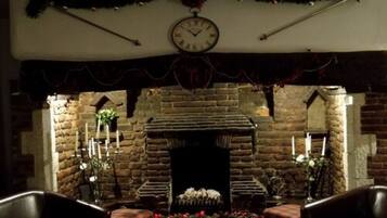 A cozy room with a stone fireplace, leather chairs, and festive decorations.