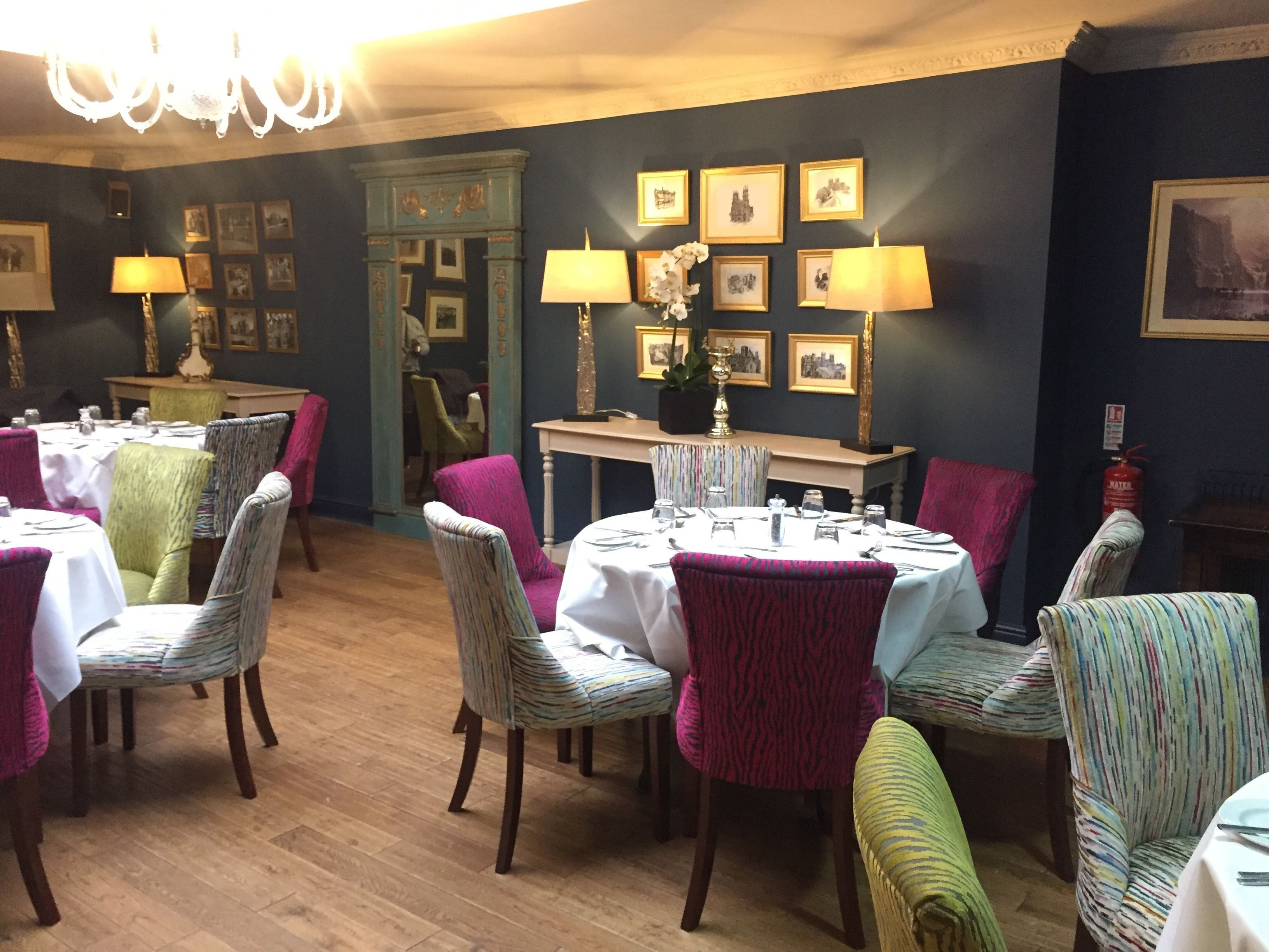 A dining area with round tables, chairs, and wall-mounted lamps.