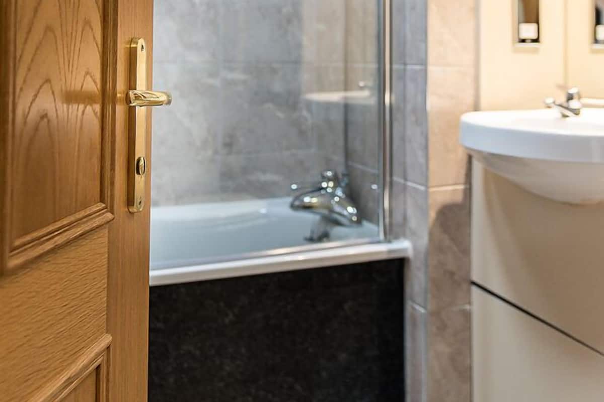 A bathroom with a glass shower enclosure, a bathtub, and a sink.