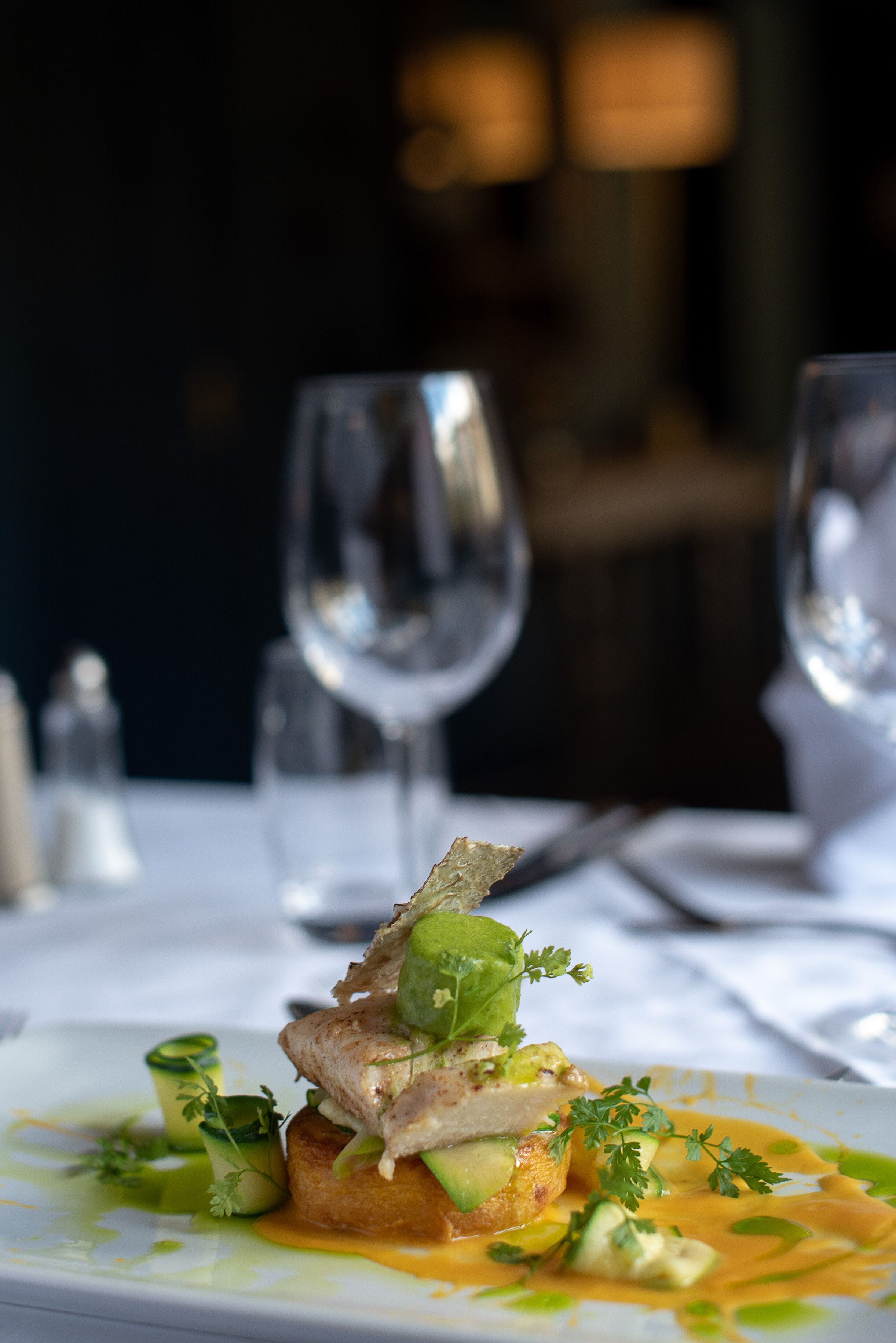 Une table à manger avec une assiette de nourriture, deux verres à vin et une fourchette.