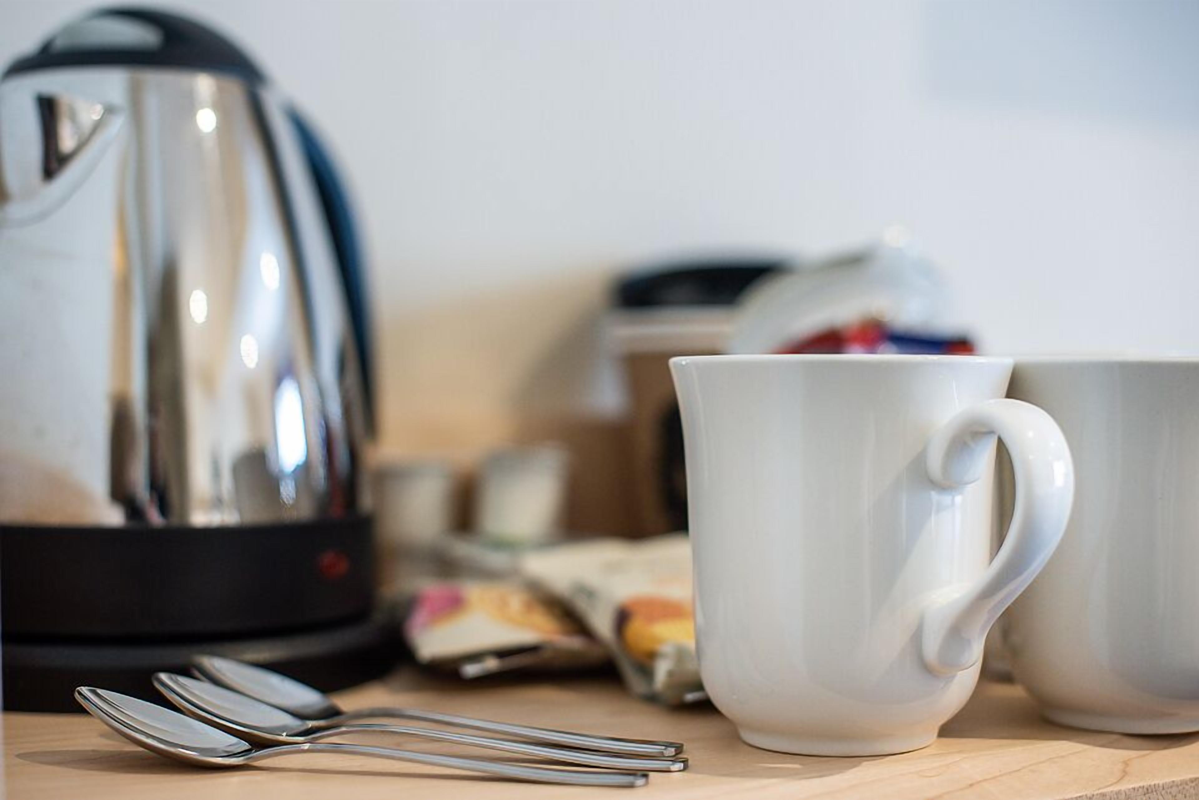 A kitchen area with a kettle, two white mugs, and a packet of tea.