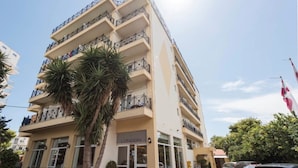 Un hotel de varios pisos con balcones, palmeras y una bandera.