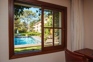 Una habitación con un ventanal grande con vistas a una piscina y un jardín ajardinado.