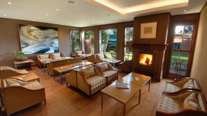 Un salón amplio con asientos cómodos, una chimenea y ventanas grandes con vistas al exterior.