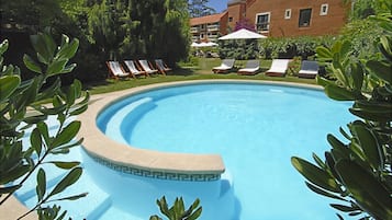 Una piscina cubierta, una piscina al aire libre, sombrillas, tumbonas