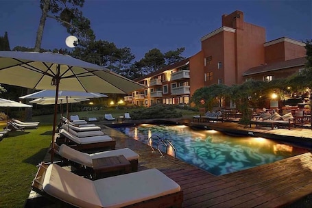 Una piscina techada, una piscina al aire libre, sombrillas