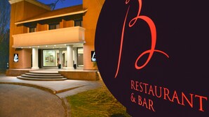 Un edificio con un gran letrero iluminado con la letra 'B' y la inscripción 'RESTAURANT & BAR' a la derecha.