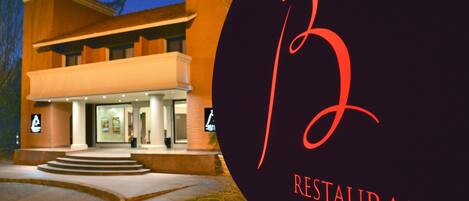 Un edificio con un gran letrero iluminado con la letra 'B' y la inscripción 'RESTAURANT & BAR' a la derecha.