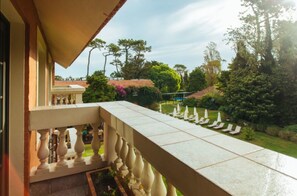 Un balcon donnant sur un jardin, avec une fontaine et des arbres.