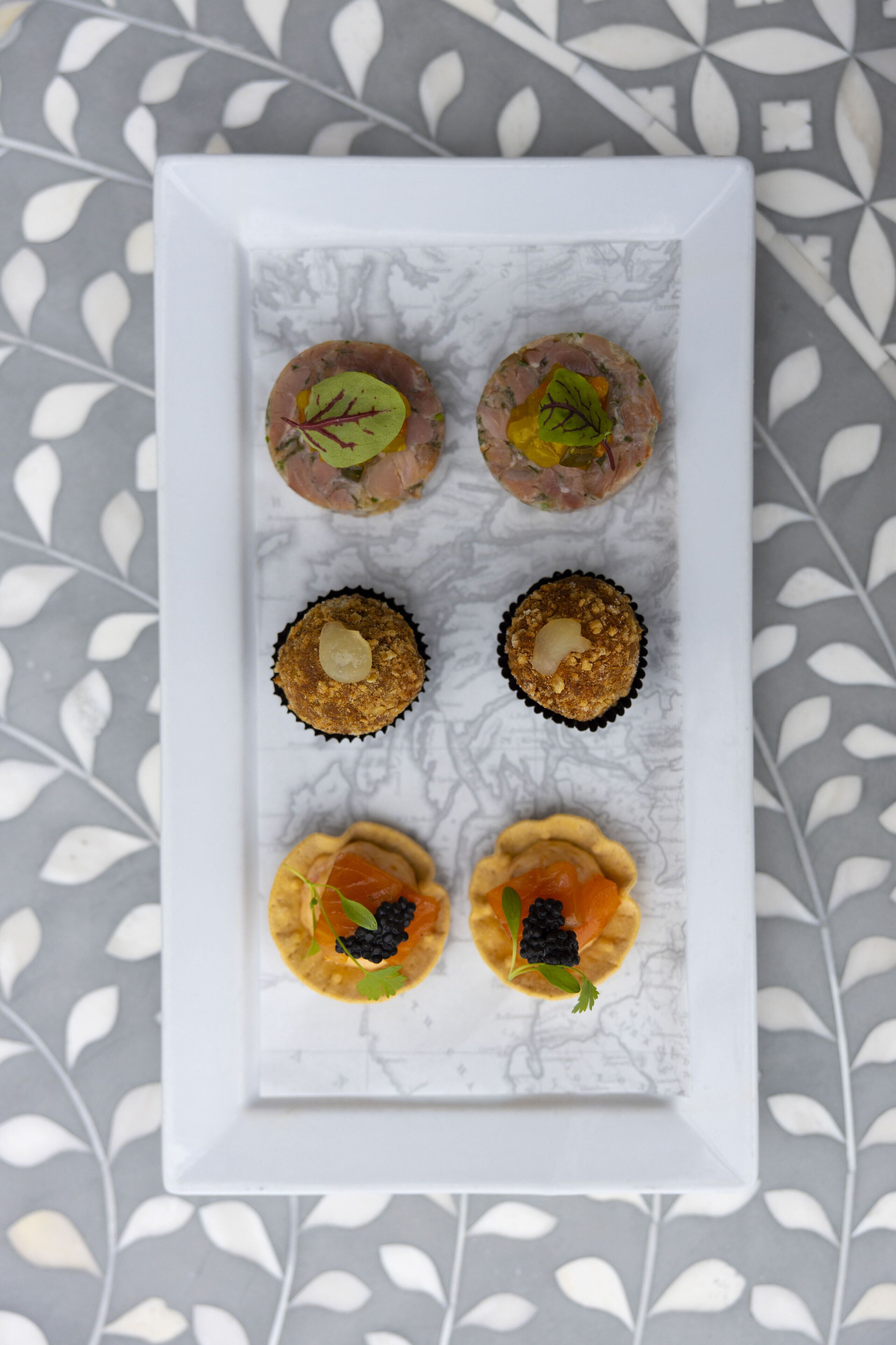 A white rectangular plate with six food items arranged in two rows of three.