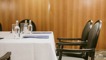 Une table de conférence avec des bouteilles d’eau, un dossier bleu et une nappe blanche.