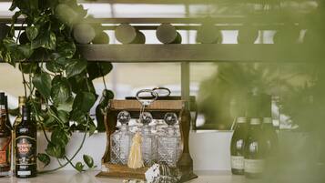 A bar area with bottles of Havana Club and Vagoletto wine, a decorative glass bottle holder, and a hanging plant.