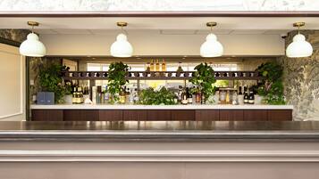 A bar area with a wooden counter, hanging pendant lights, and various bottles and glasses.
