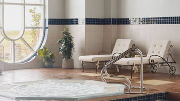Un área de piscina con un jacuzzi, sillas de descanso y vistas al exterior a través de grandes ventanales.