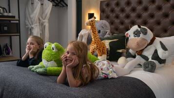 Cozy bedroom with a tufted headboard, patterned bedspread, and plush toys.