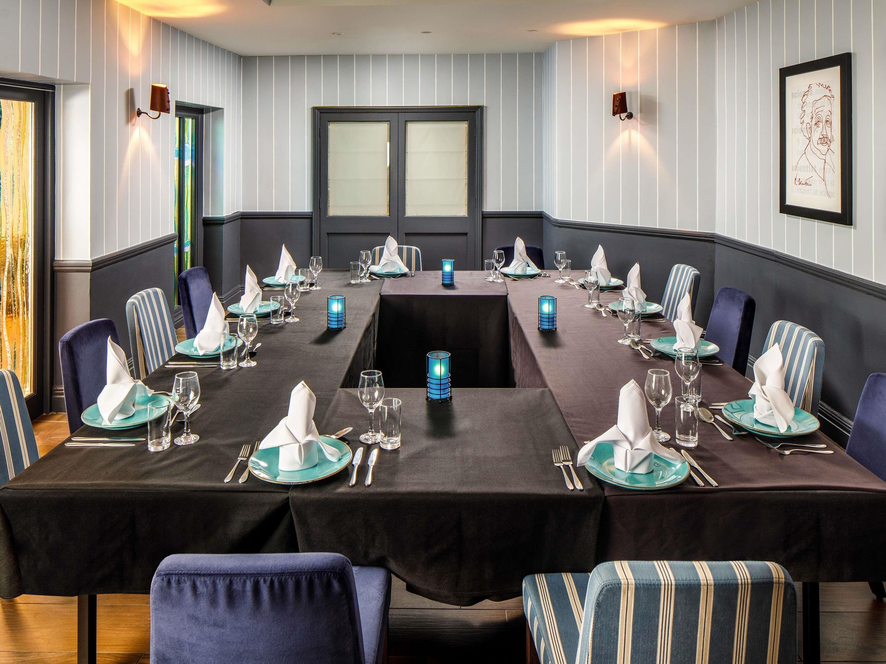 A conference room with a long table set for a meeting, surrounded by chairs, and equipped with table lamps.