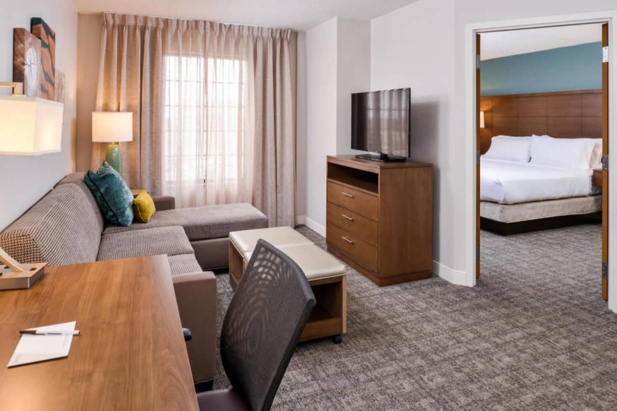 Une chambre d’hôtel avec un canapé, un bureau, une télévision et un lit.