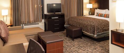 A hotel room with a bed, a TV, a desk, a chair, and a small table.