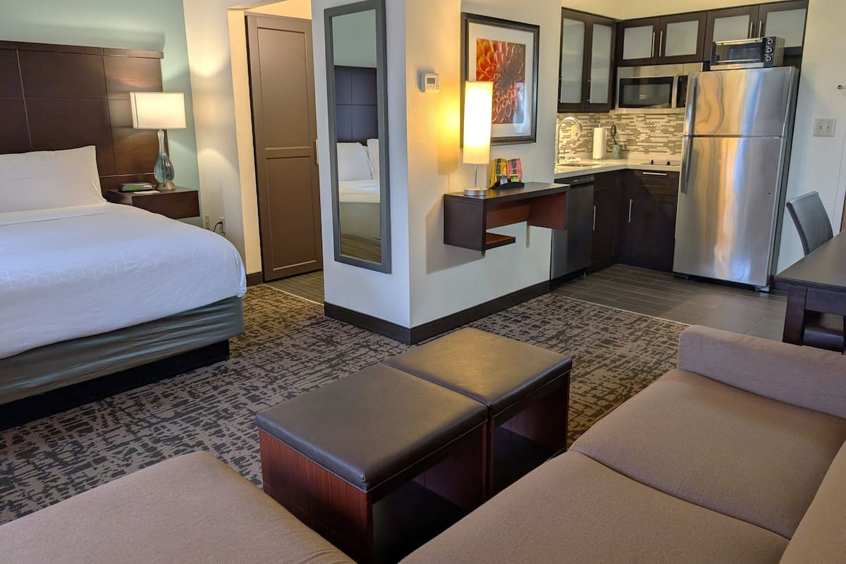Une chambre d’hôtel équipée d’un lit, d’un bureau, d’un réfrigérateur et d’un coin salon.