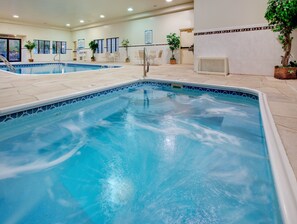 An indoor swimming pool with clear water, surrounded by tiled walls and potted plants. - Staybridge Suites Downtown Peoria by IHG (Peoria)