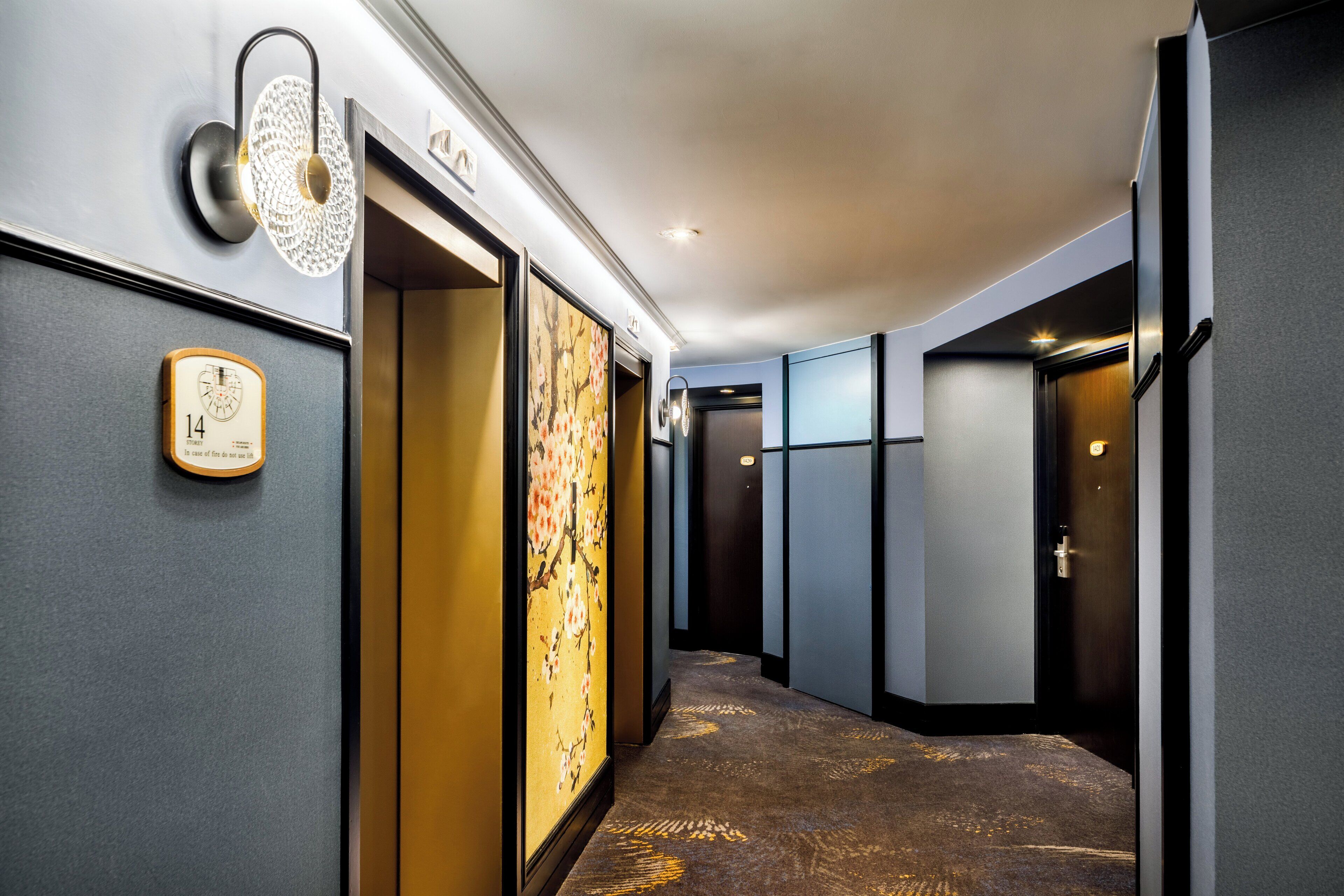 A hallway with a carpeted floor, a wall-mounted clock, and a decorative panel.