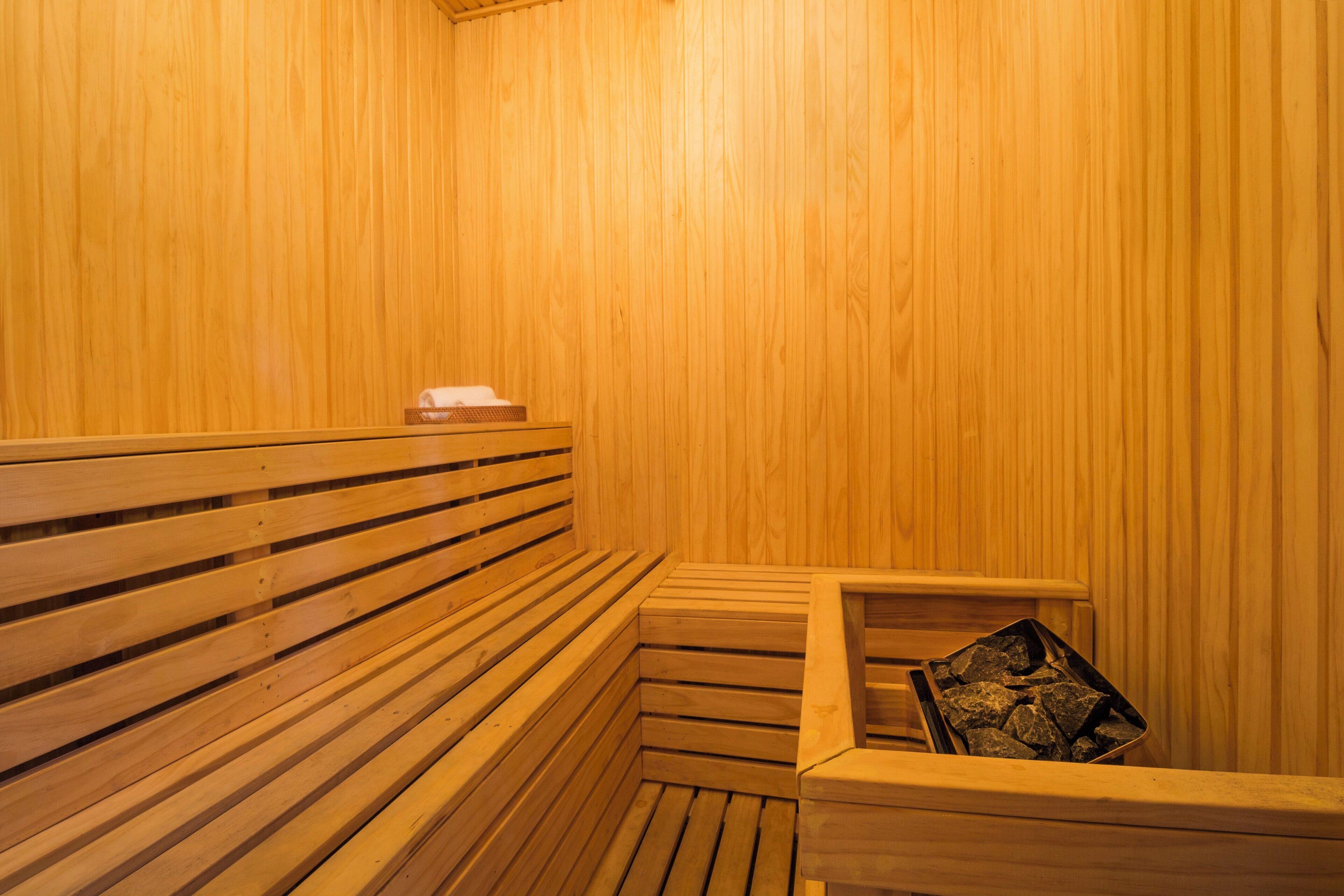 A wooden sauna with benches and a stone tray.