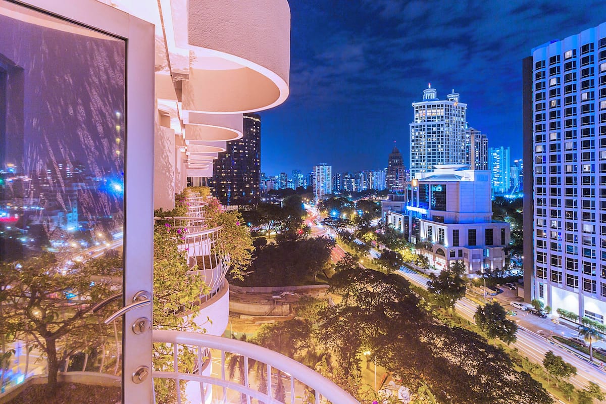Une vue nocturne d’une ville, avec ses bâtiments illuminés et un balcon offrant une vue sur la ville.