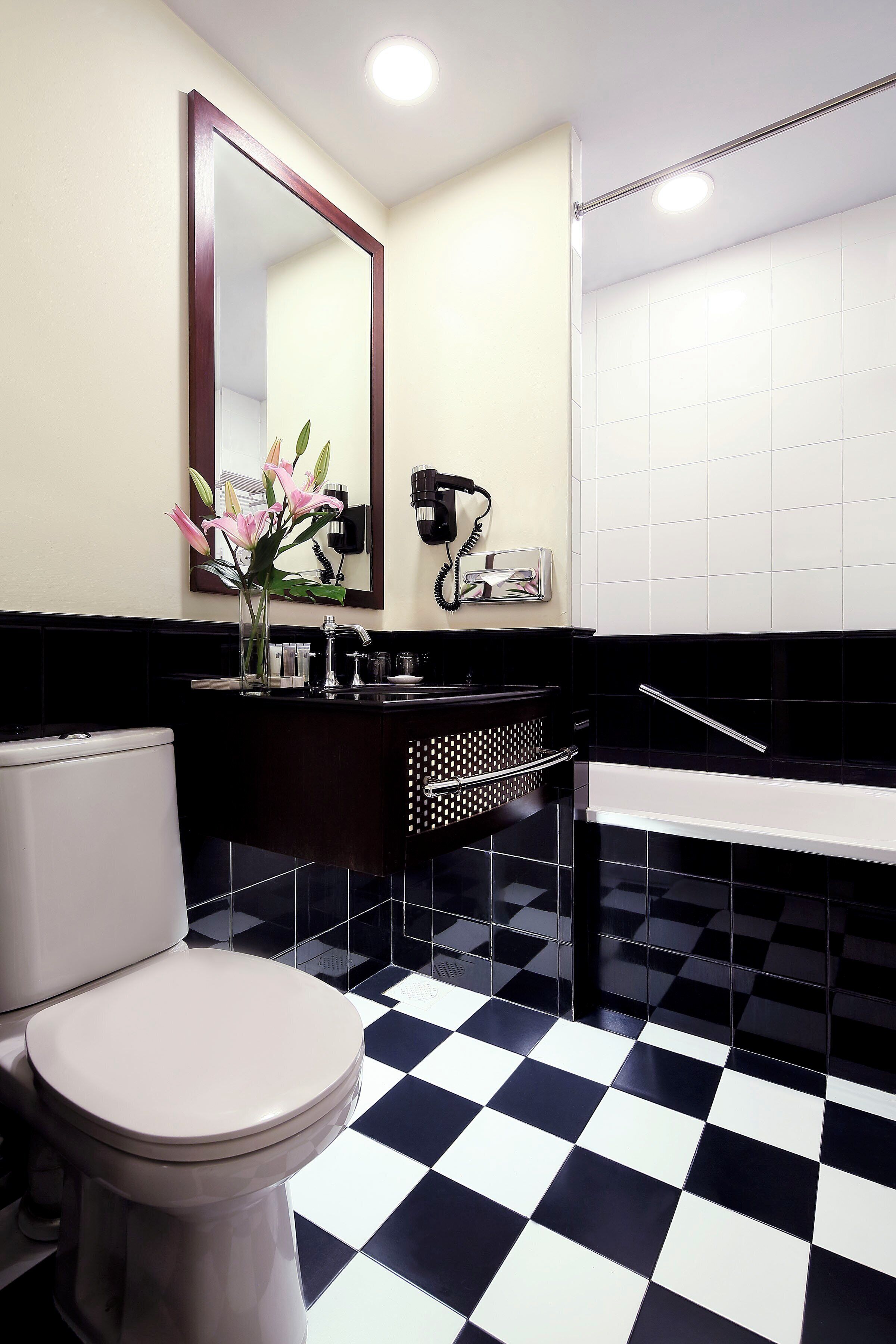 A bathroom with a black and white checkered floor, a white toilet, a sink with a mirror, and a towel rack.