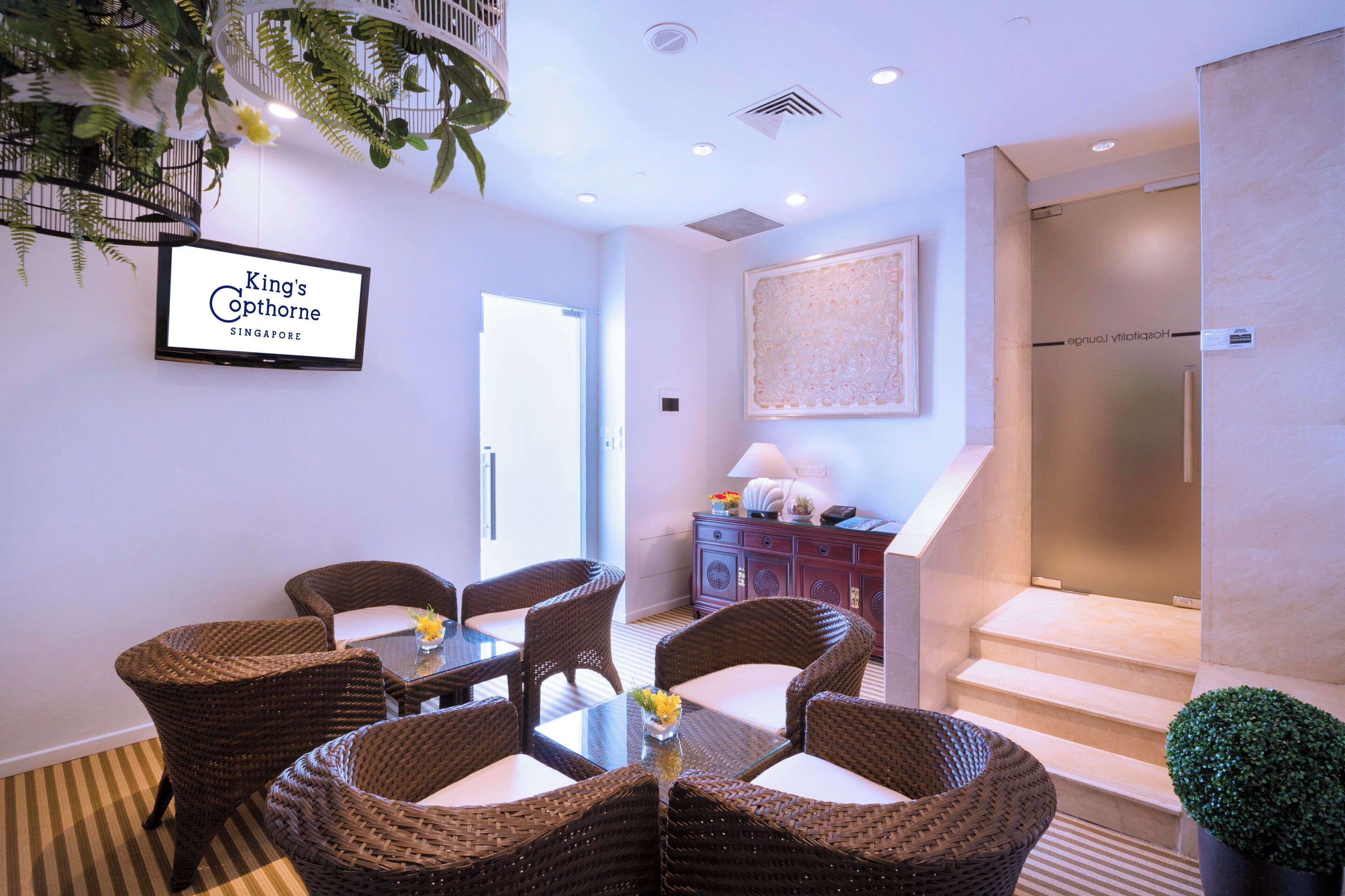 A hotel lobby with wicker furniture, a framed sign, and a staircase.