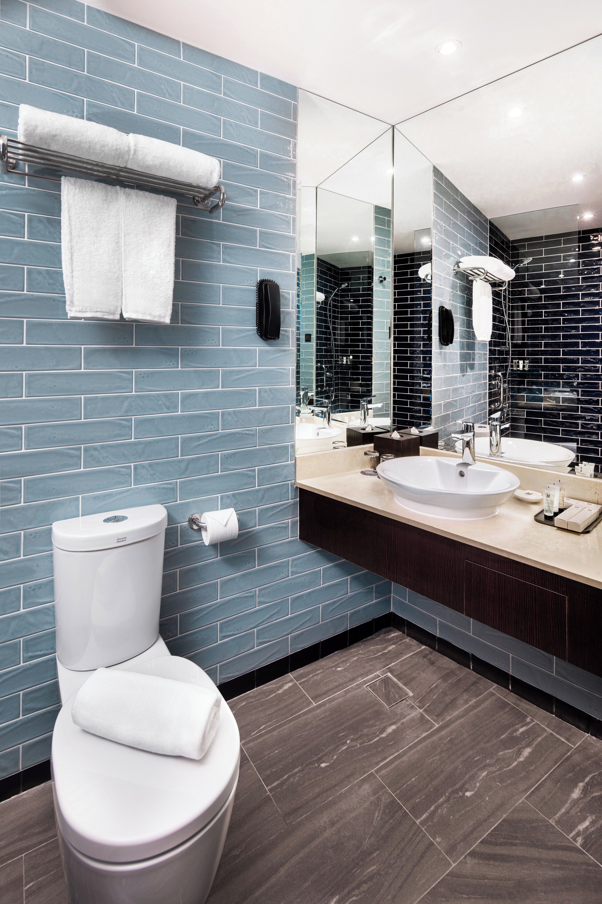 A modern bathroom with a toilet, sink, and large mirror.