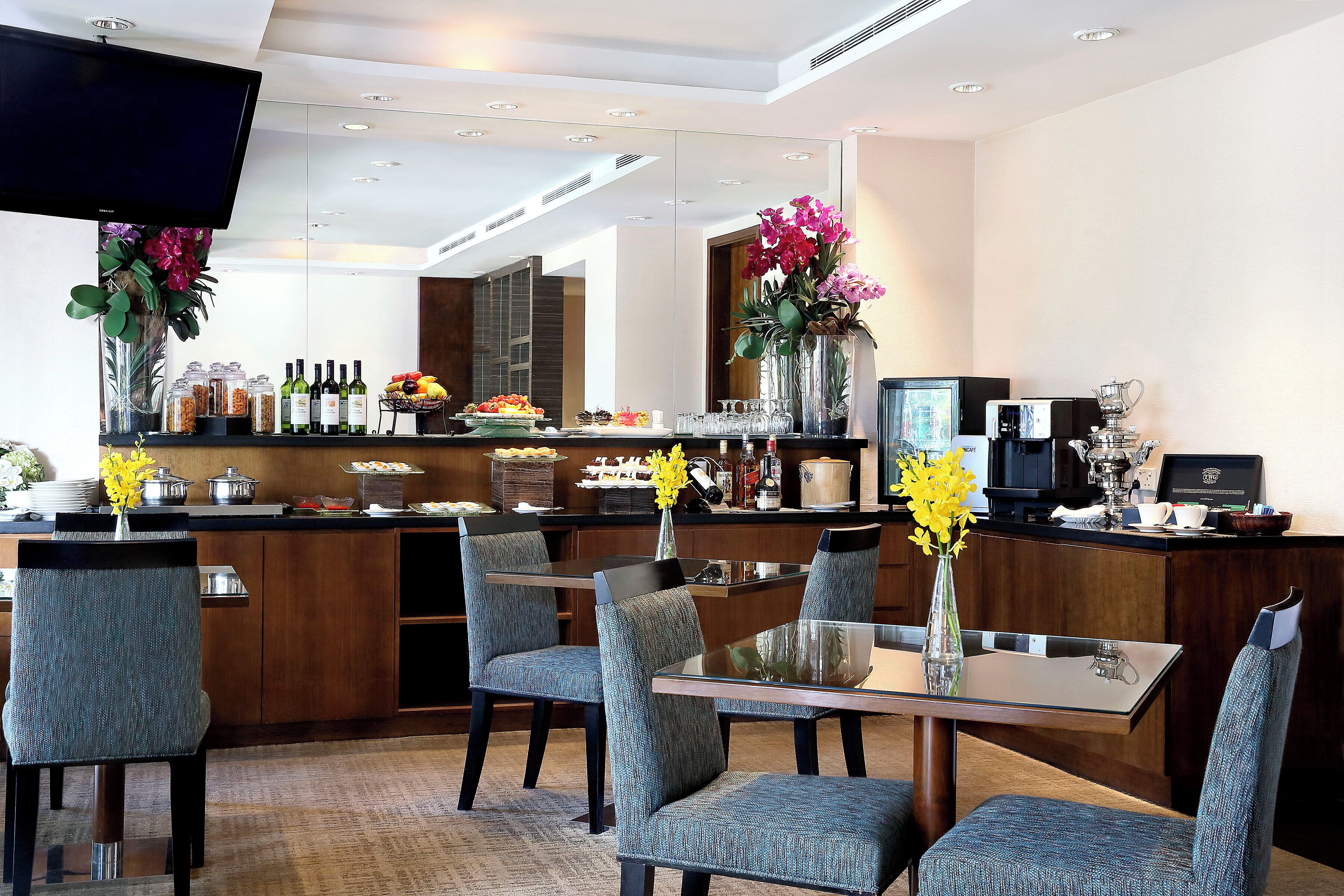 A modern hotel lobby with a bar area, seating, and a television.