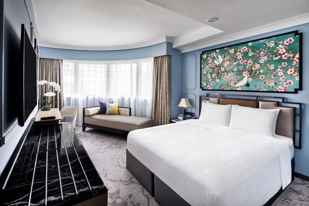 Une chambre d’hôtel dotée d’un grand lit, d’un canapé, d’un bureau avec un téléviseur à écran plat et d’une grande œuvre d’art florale accrochée au mur.