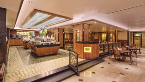 Eine Hotelhalle mit Barbereich in der Mitte, Sitzgelegenheiten und einer Treppe zu einer oberen Ebene.