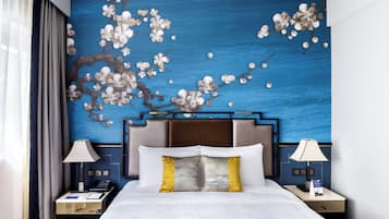 A hotel room with a large bed, two bedside tables, a nightstand, and a wall mural of flowers.