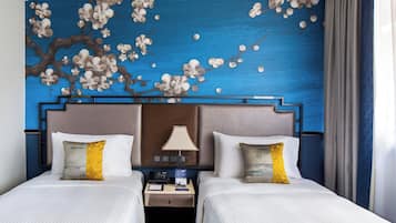 A hotel room with two beds, a nightstand with a lamp, and a wall mural of flowers.