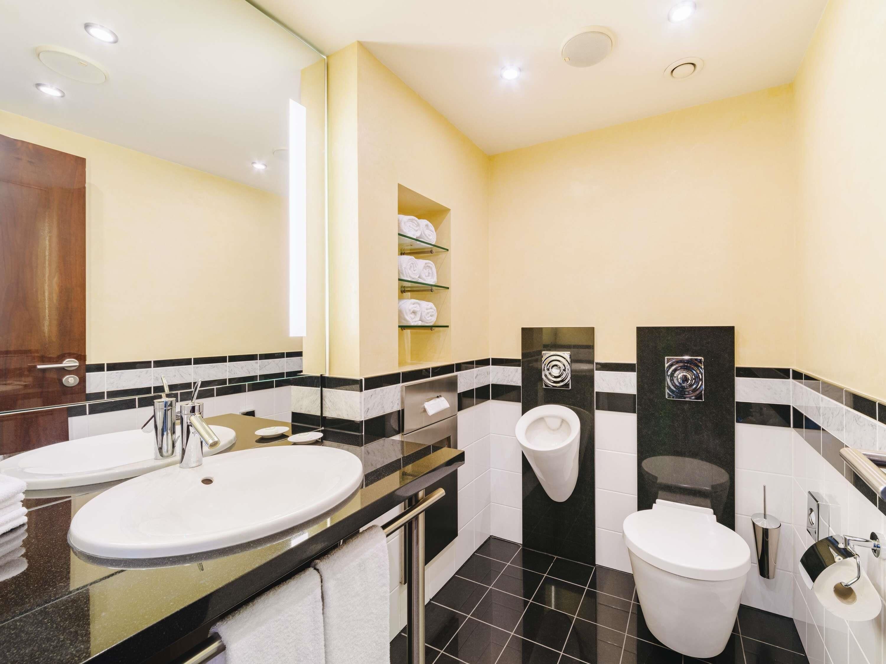 Un bagno moderno con due lavandini, un water e una zona doccia.