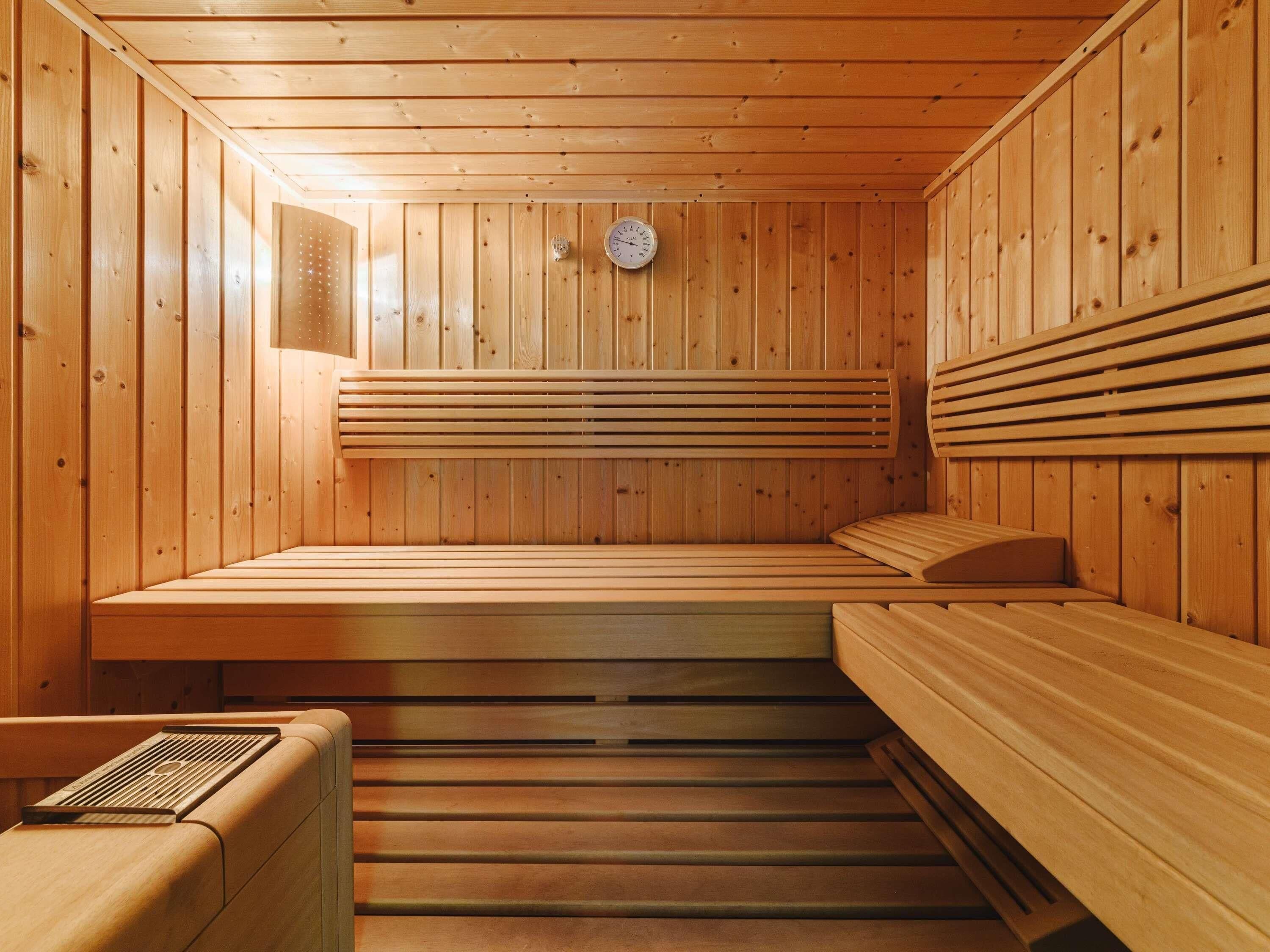 A wooden sauna with benches and a sloped ceiling.