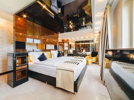 A modern hotel room with a large bed, a desk, and a seating area.