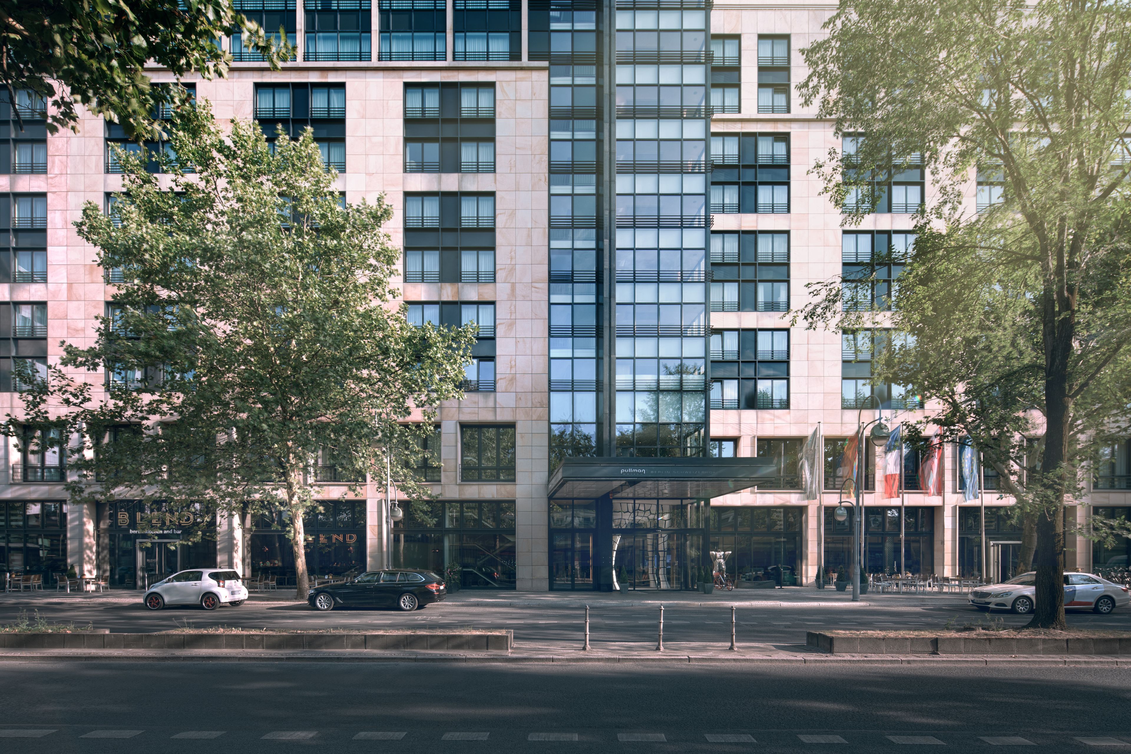 A modern building with a glass facade, multiple floors, and a prominent entrance with a covered area.
